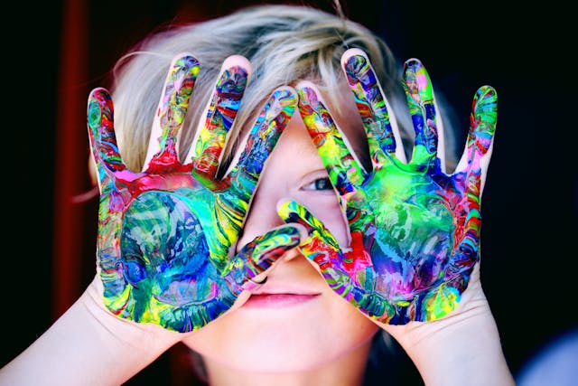 a boy with painted hands in front of his face